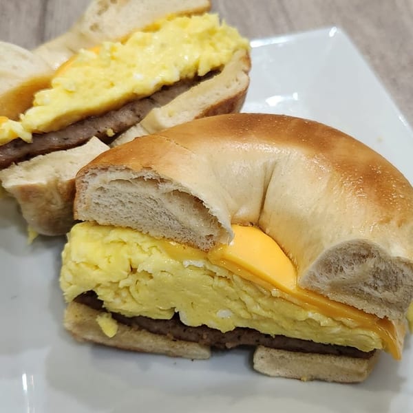 Two Thorn Hill Cafe breakfast bagels with scrambled eggs, cheese, and sausage on a white plate.