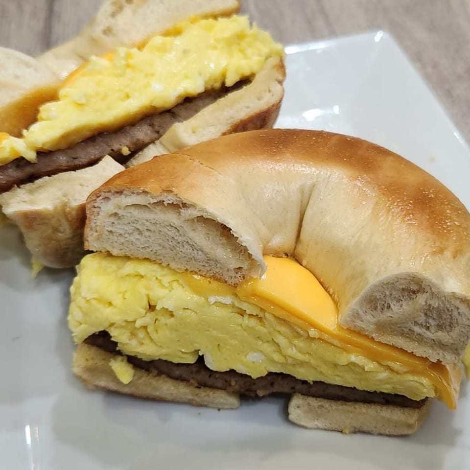 Two Thorn Hill Cafe breakfast bagels with scrambled eggs, cheese, and sausage on a white plate.