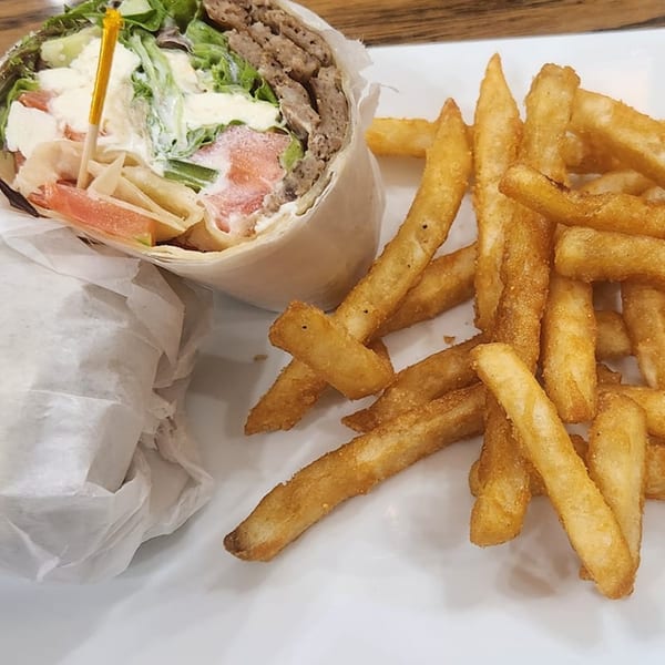 A Thorn Hill Cafe gyro wrap with meat, lettuce, tomatoes, and sauce, served with golden french fries.