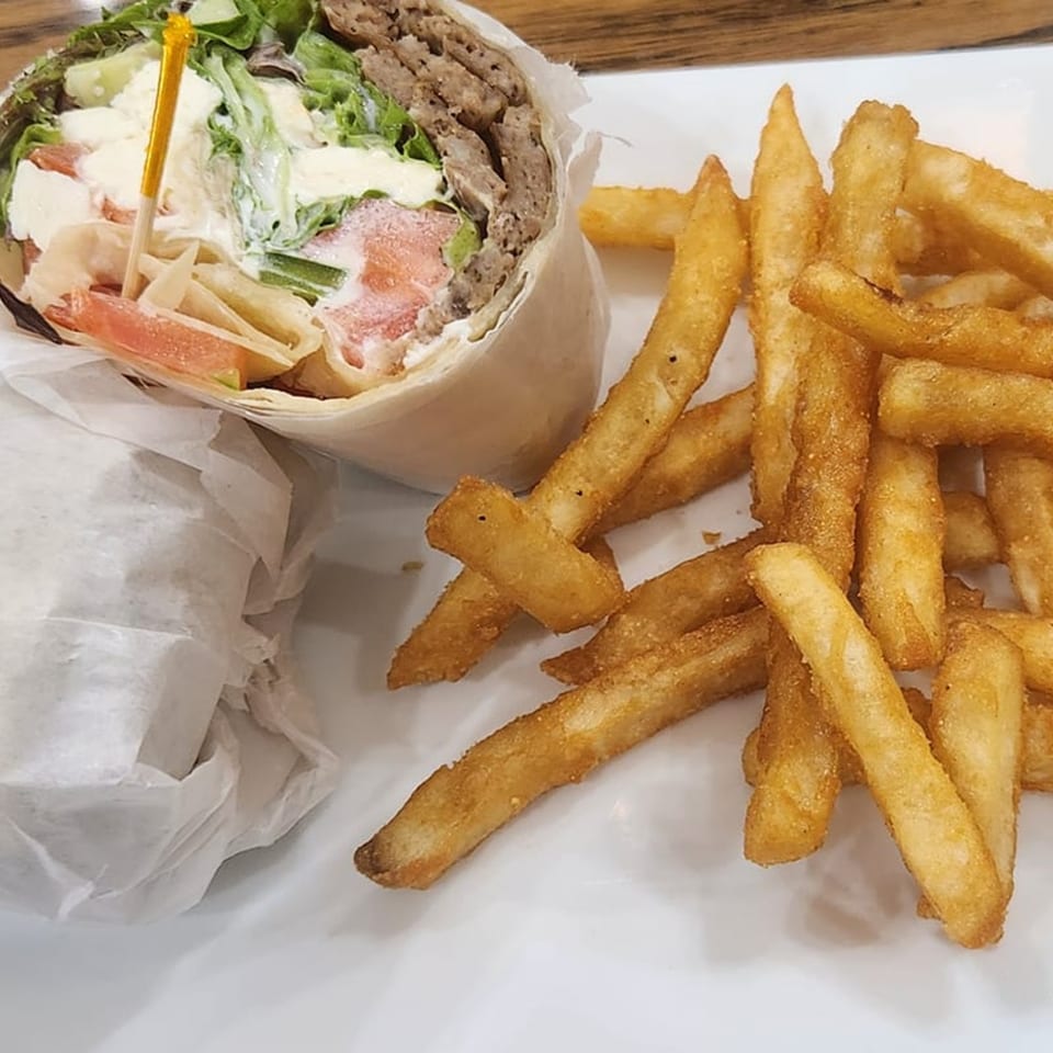A Thorn Hill Cafe gyro wrap with meat, lettuce, tomatoes, and sauce, served with golden french fries.